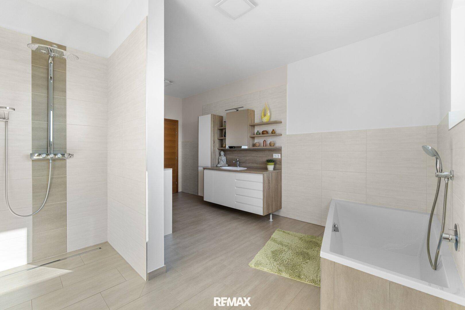 Geräumiges Badezimmer mit begehbarer Dusche, Badewanne und modernem Waschtisch in hellen Farbtönen.