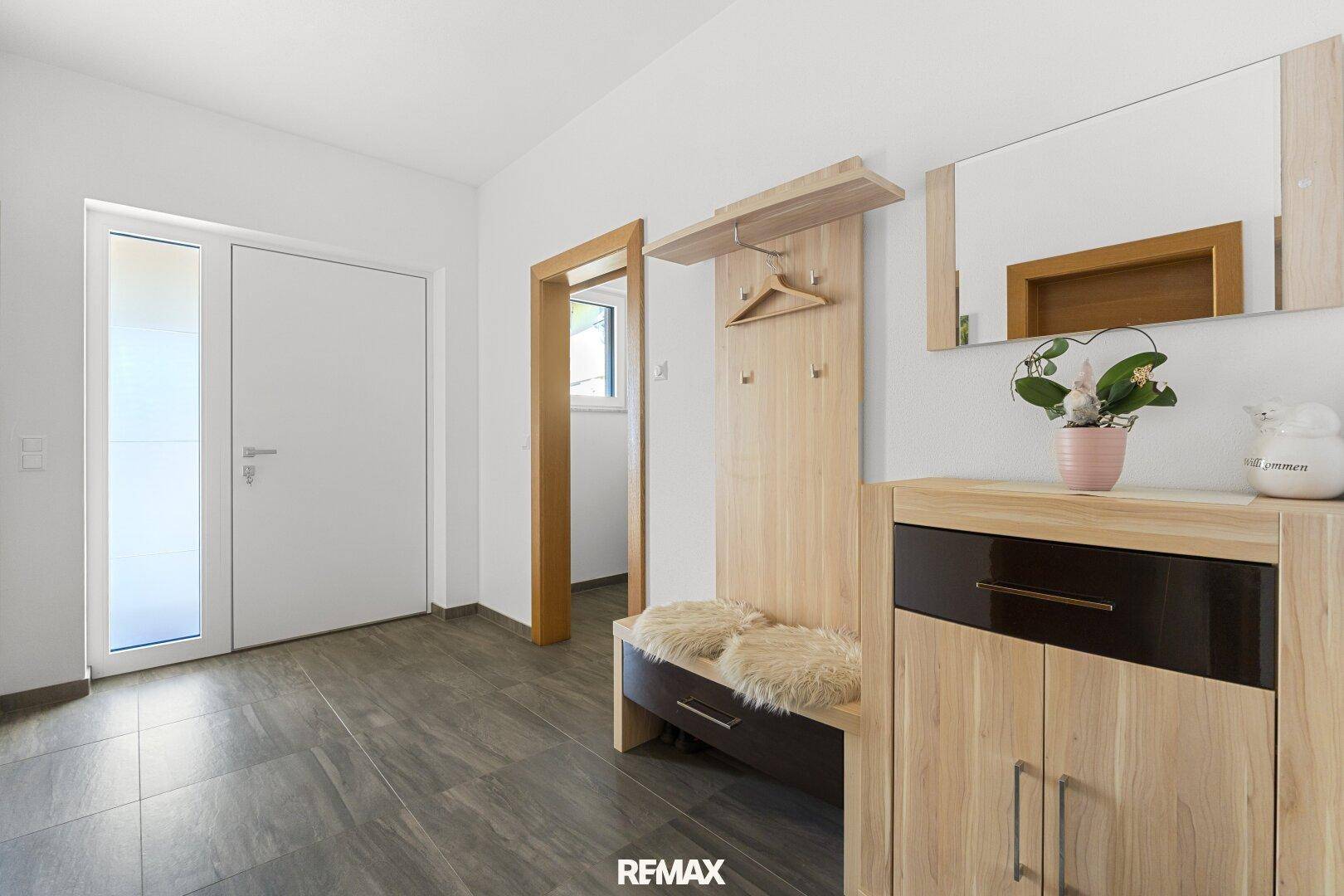 Freundlicher Eingangsbereich mit Garderobe, Sitzbank und Spiegel, ausgestattet mit modernen Fliesen.