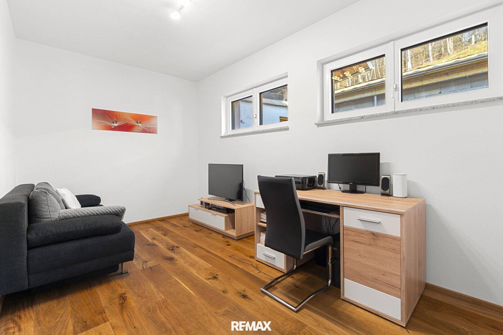 Funktionaler Arbeitsbereich mit Schreibtisch, Sofa und Holzboden, ideal für Home-Office.