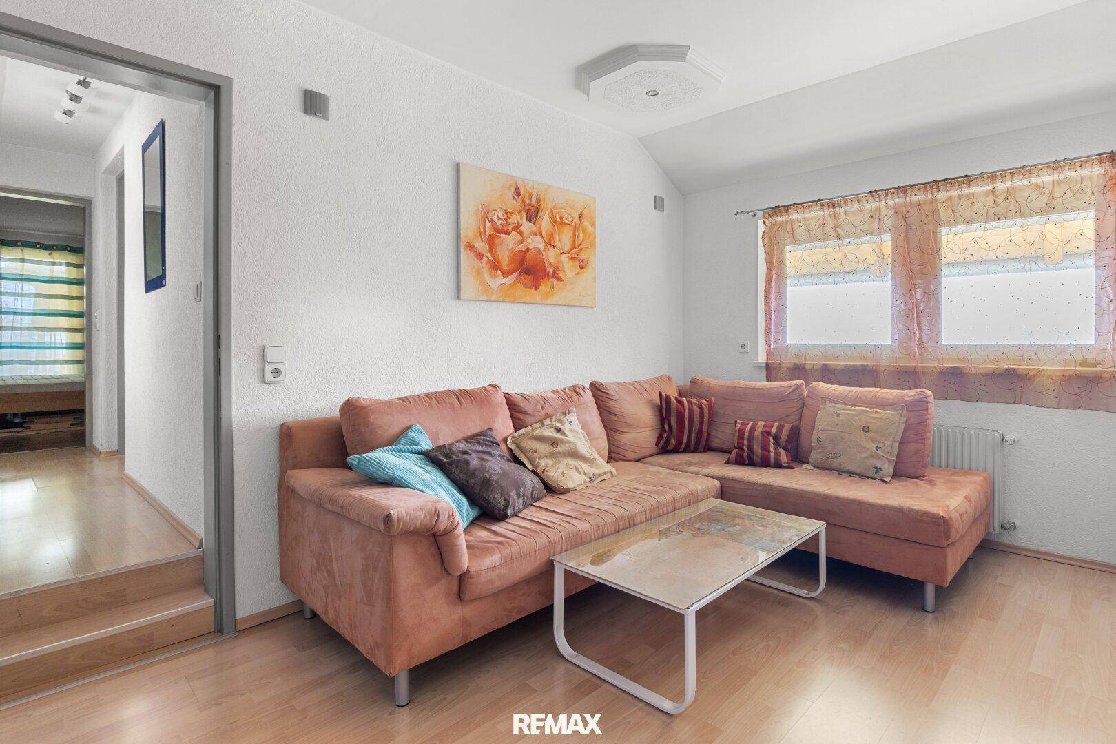 Gemütliches Wohnzimmer mit Ecksofa, Couchtisch und Laminatboden, hell und einladend.