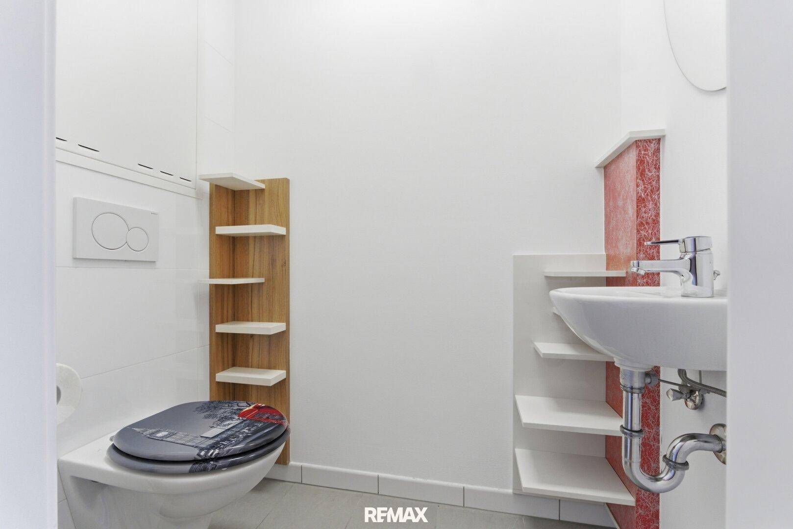 Kleines Gäste-WC mit wandhängender Toilette, Waschbecken und praktischen Ablageflächen.