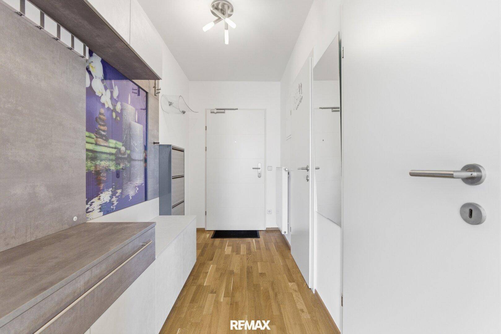 Heller Eingangsbereich mit Holzboden, Garderobe und moderner Beleuchtung.
