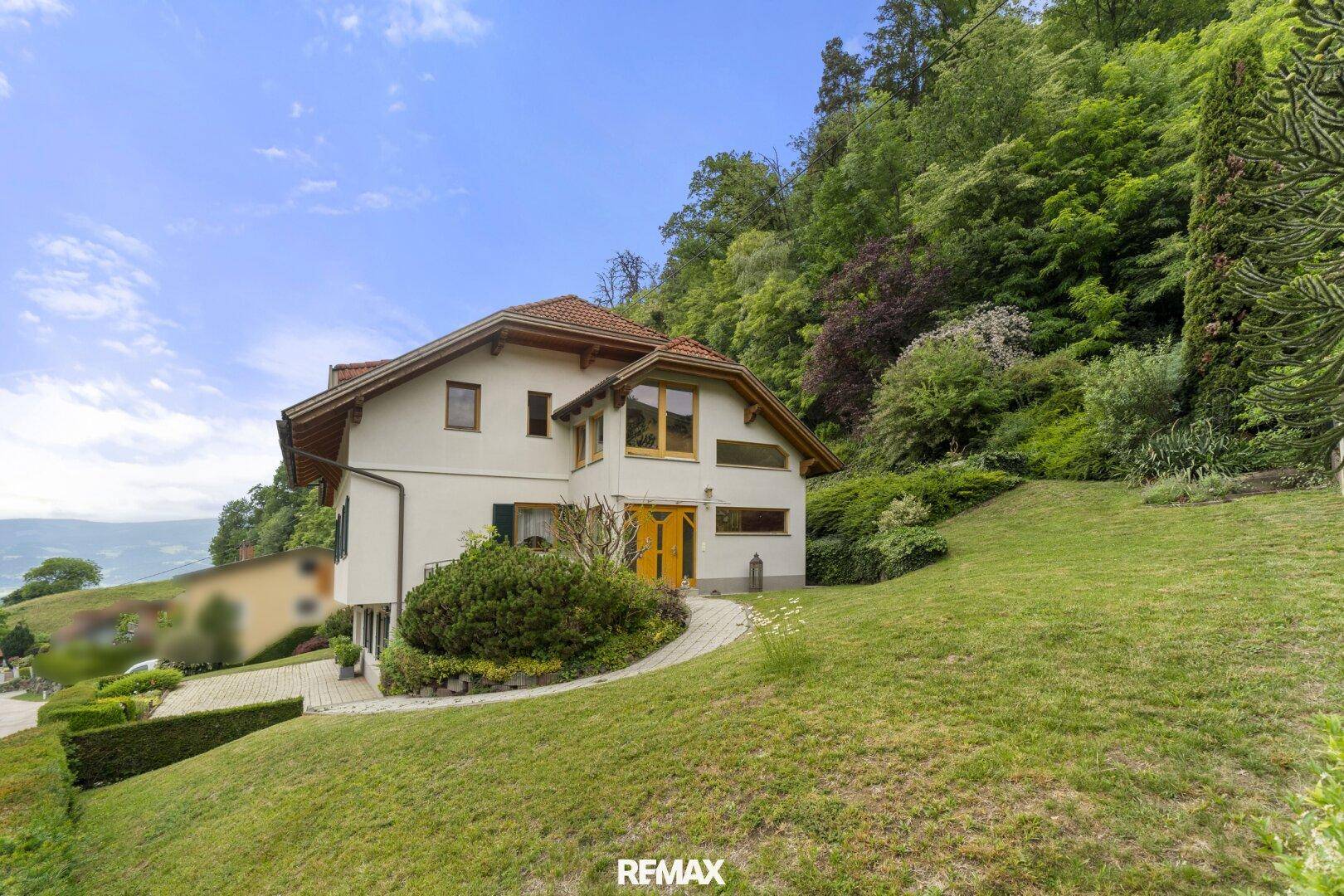 Freistehendes Haus mit großem Rasenbereich und weitem Blick auf die umliegende Landschaft.