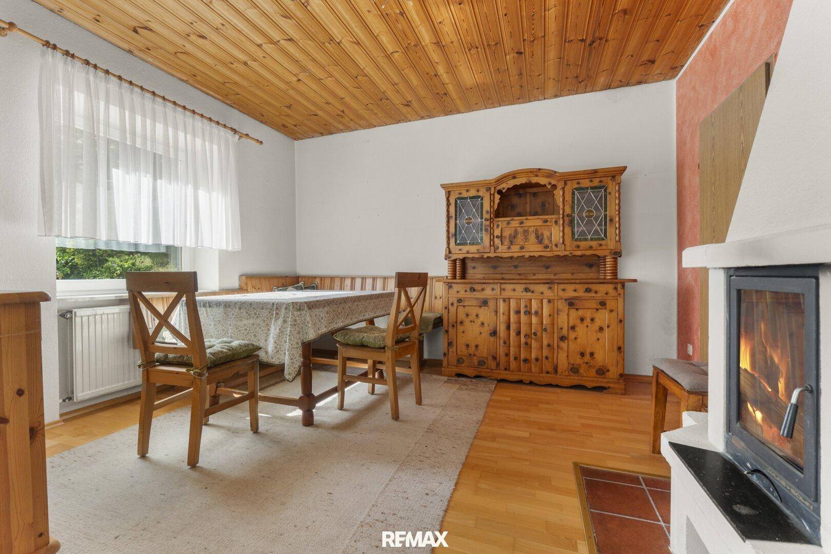 Rustikaler Essbereich mit Holztisch, Sitzbank und einem traditionellen Holzschrank, Holzbalkendecke.