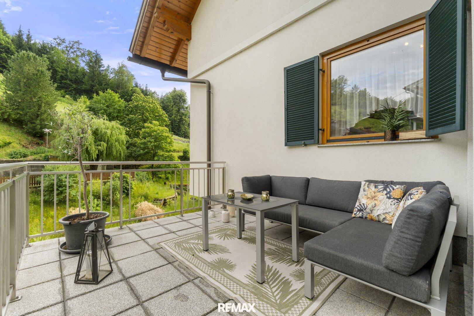 Moderner Balkon mit bequemen Outdoor-Möbeln und weitem Blick über die grüne Landschaft.