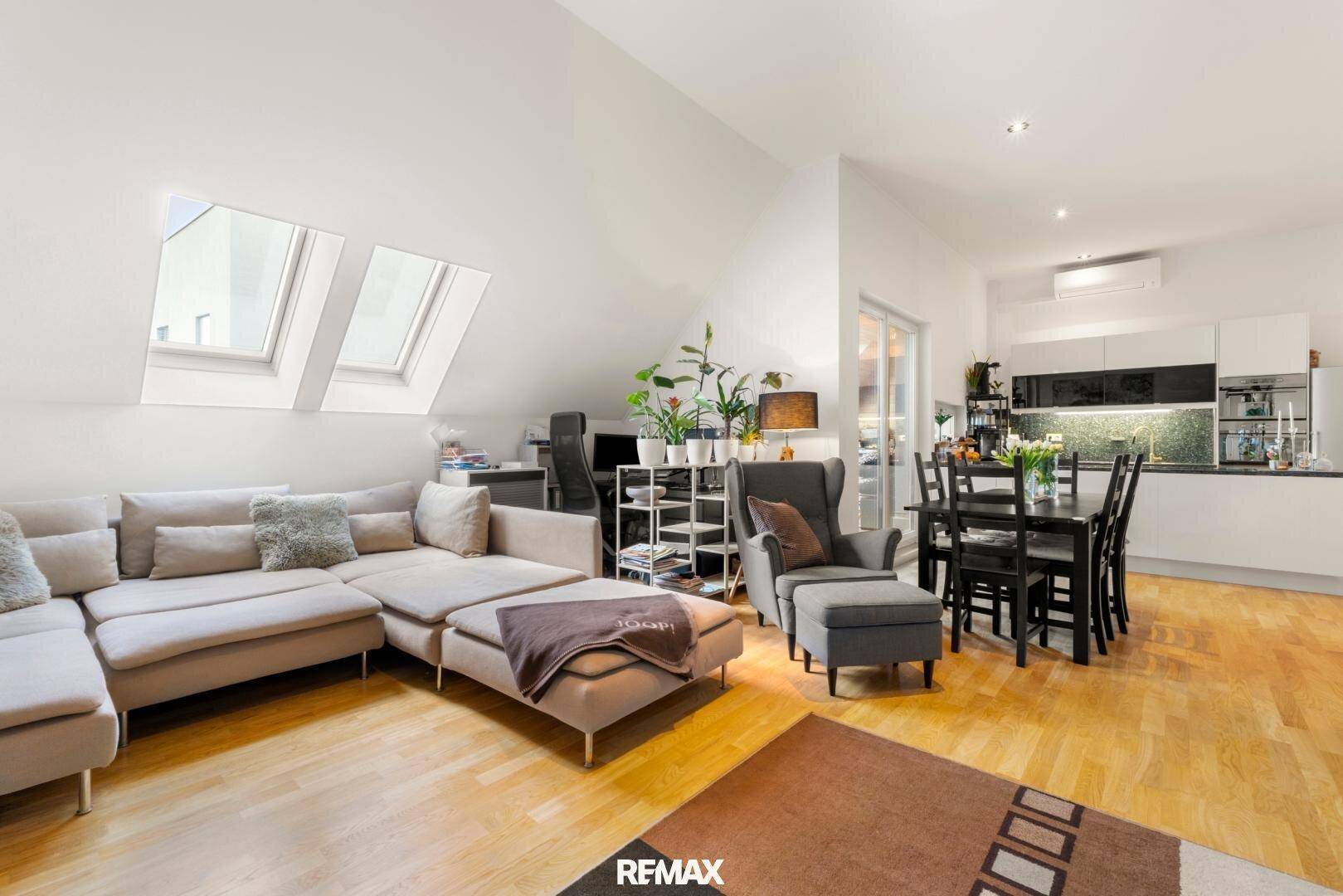 Geräumiger offener Wohn- und Essbereich mit bequemer Couch und moderner Küche im Hintergrund.