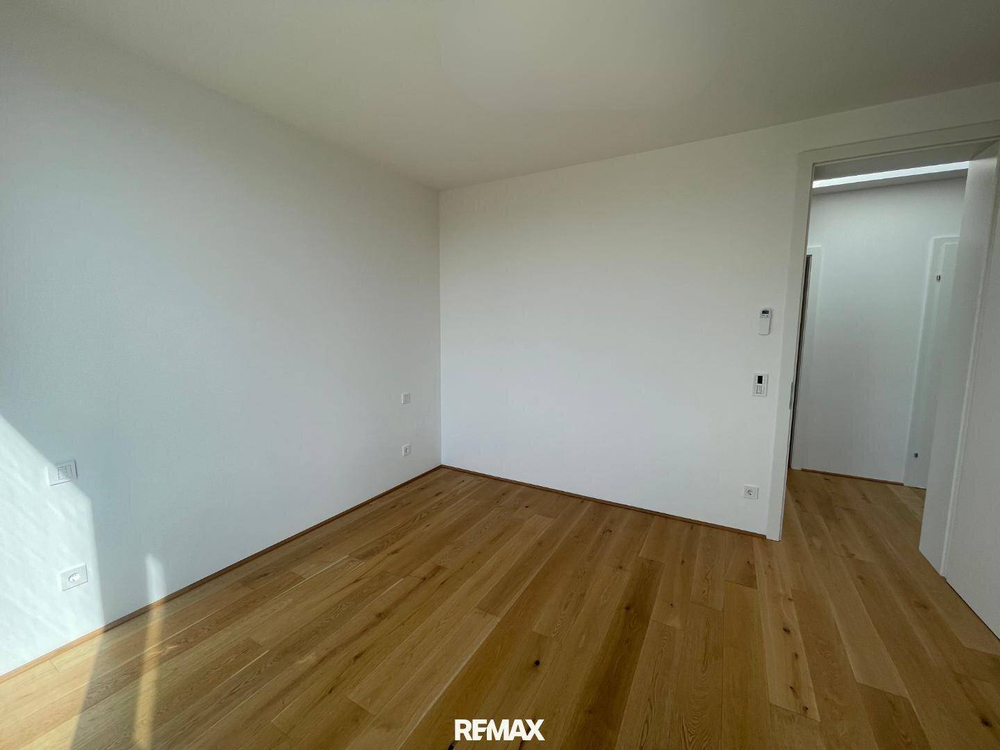 Leeres Zimmer mit hellem Holzboden und weißen Wänden, bereit zur individuellen Gestaltung.