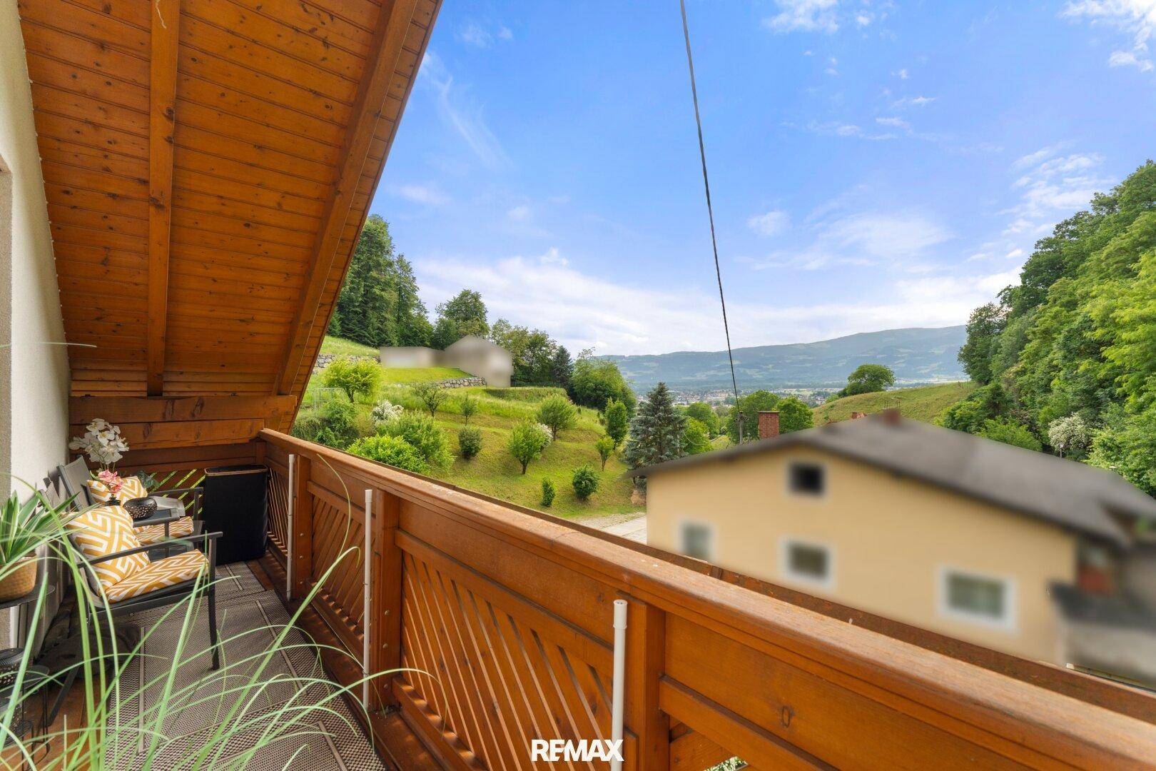 Gemütlicher Holzbalkon mit Sitzgelegenheiten und weitem Blick auf die grüne Landschaft.