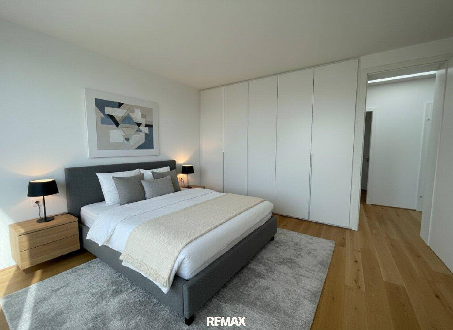 Modernes Schlafzimmer mit Doppelbett, Holzboden und integrierten weißen Einbauschränken für viel Stauraum.