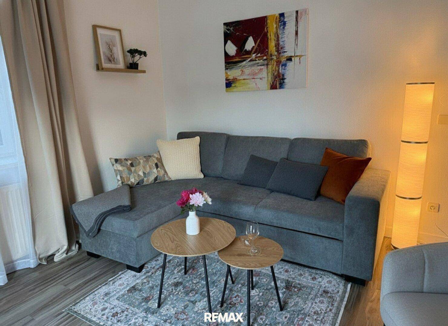 Gemütliches Wohnzimmer mit Ecksofa, Teppich und moderner Stehlampe für entspannte Abende.