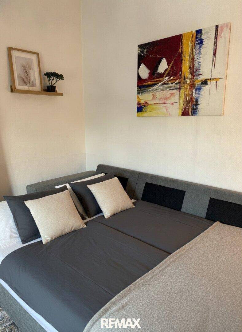 Gemütliches Schlafzimmer mit einem bequemen Bett, moderner Kunst und einer kleinen Ablage.