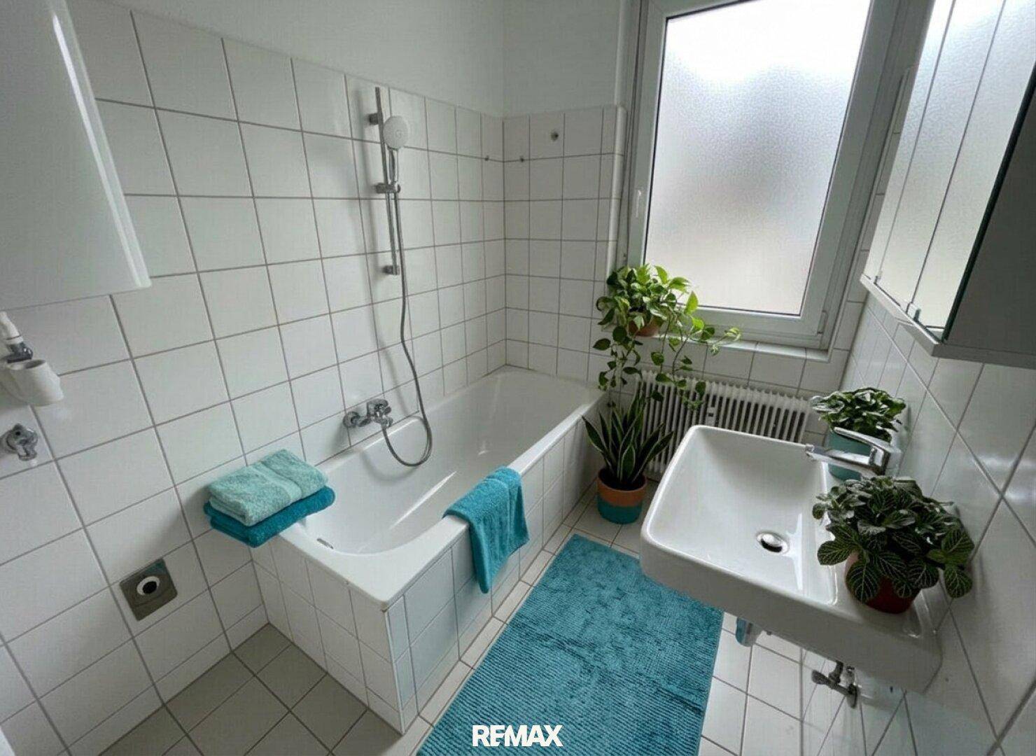 Gefliestes Badezimmer mit Badewanne, Waschbecken und Fenster für Tageslicht.