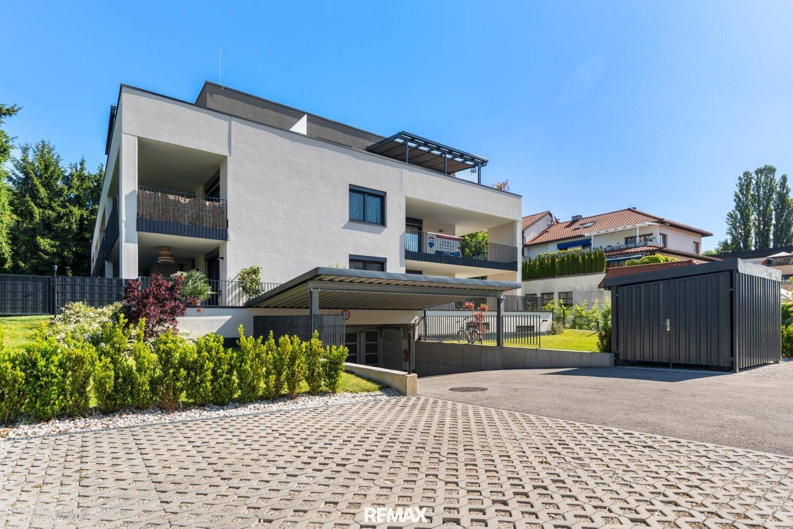 Moderne Wohnanlage mit klarer Architektur, Tiefgaragenzufahrt und gepflegter Außenanlage.