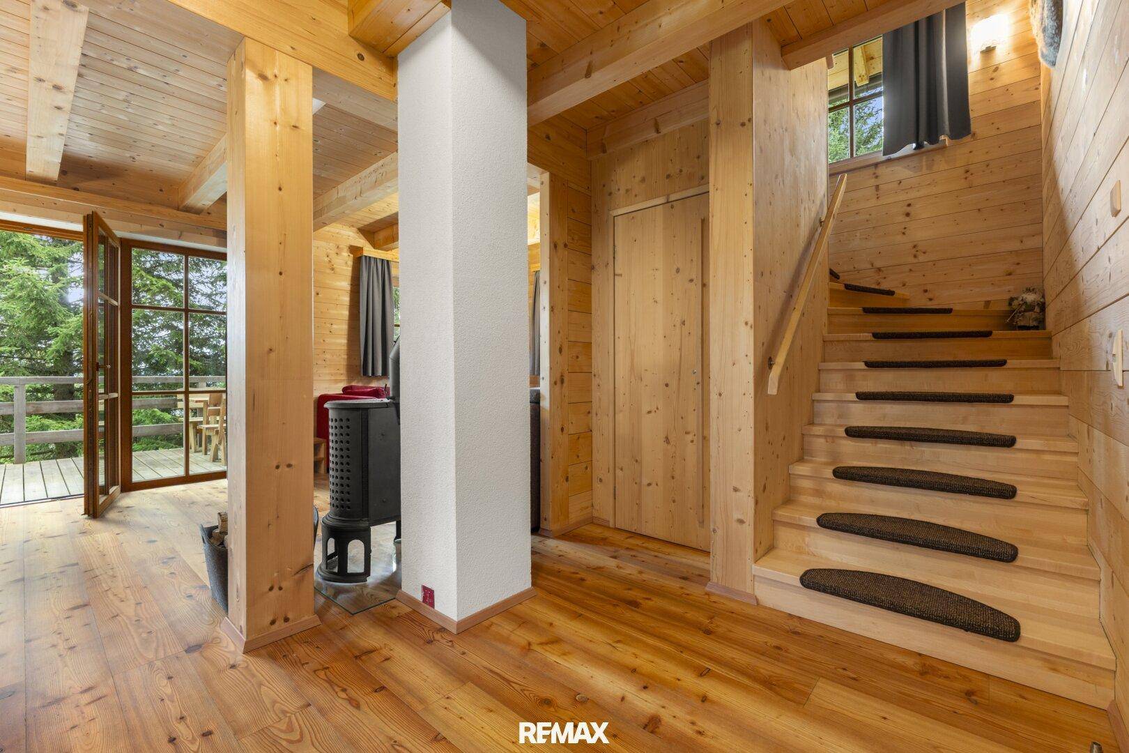 Heller Flur mit Holztreppe und Zugang zu den oberen Etagen und dem Außenbereich.