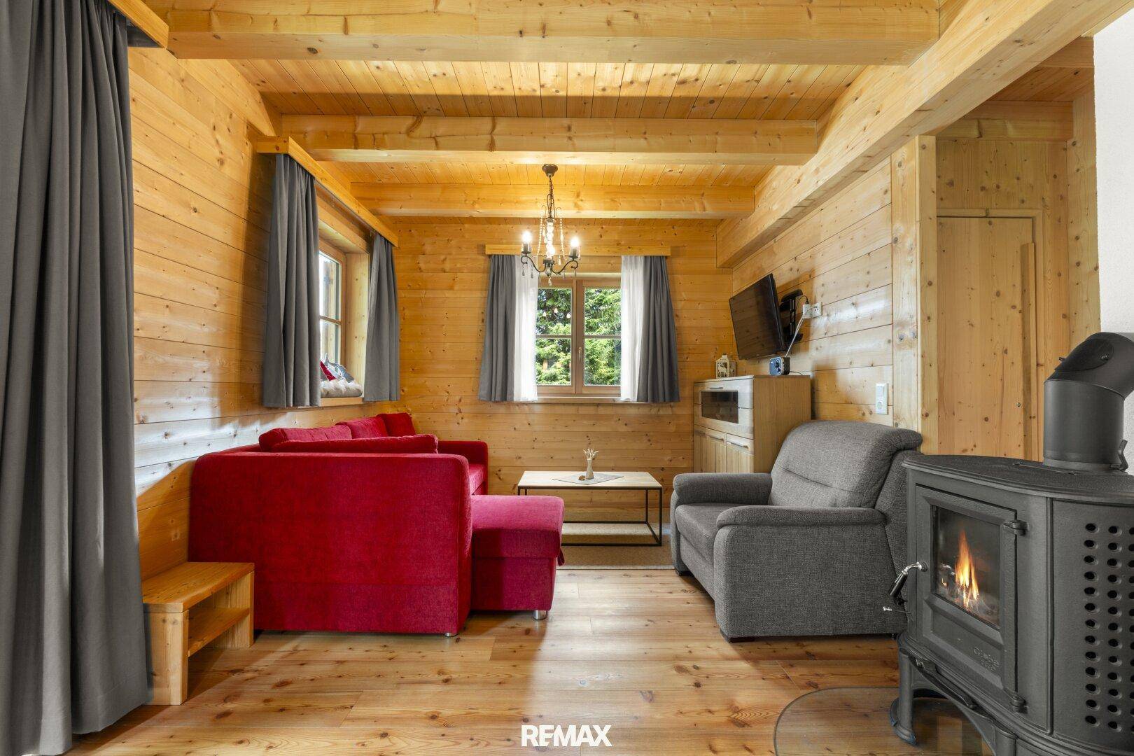 Rustikales Wohnzimmer mit Holzboden, Kaminofen und bequemen Sitzgelegenheiten.