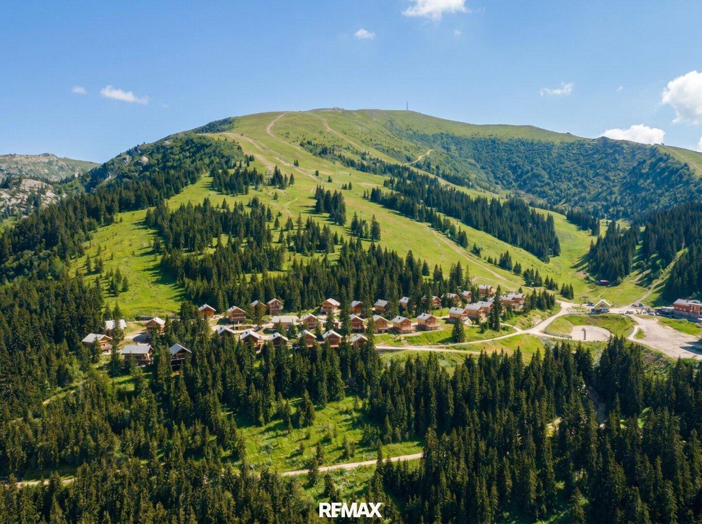 Luftaufnahme einer Chalet-Siedlung in einer malerischen Berglandschaft mit Skipisten.
