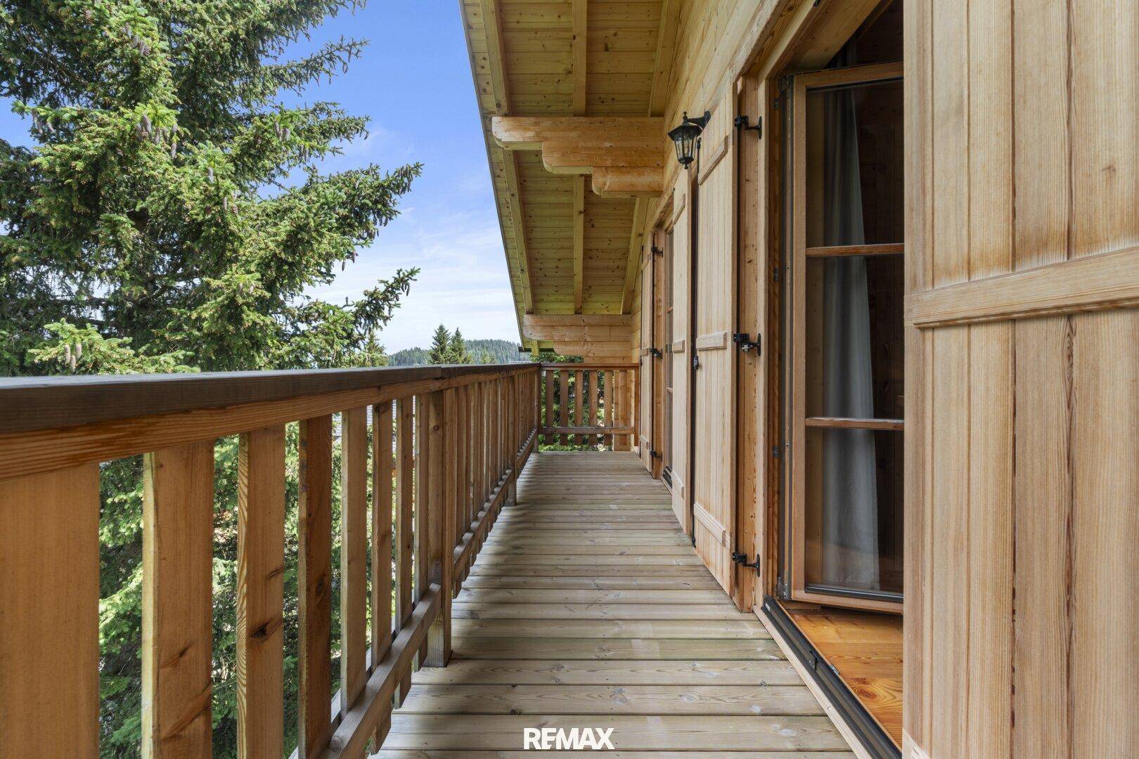 Langer Holzbalkon mit Geländer und Blick auf die umliegende Berglandschaft.