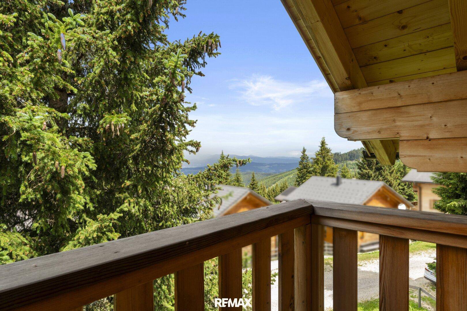 Panoramablick vom Balkon auf die grüne Berglandschaft und weitere Chalets.