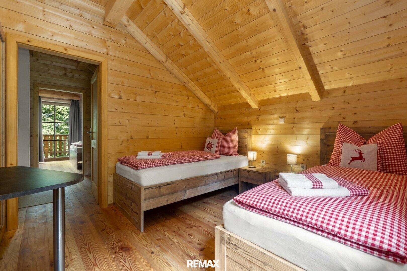 Gemütliches Schlafzimmer mit zwei Einzelbetten, Holzwänden und alpiner Dekoration.