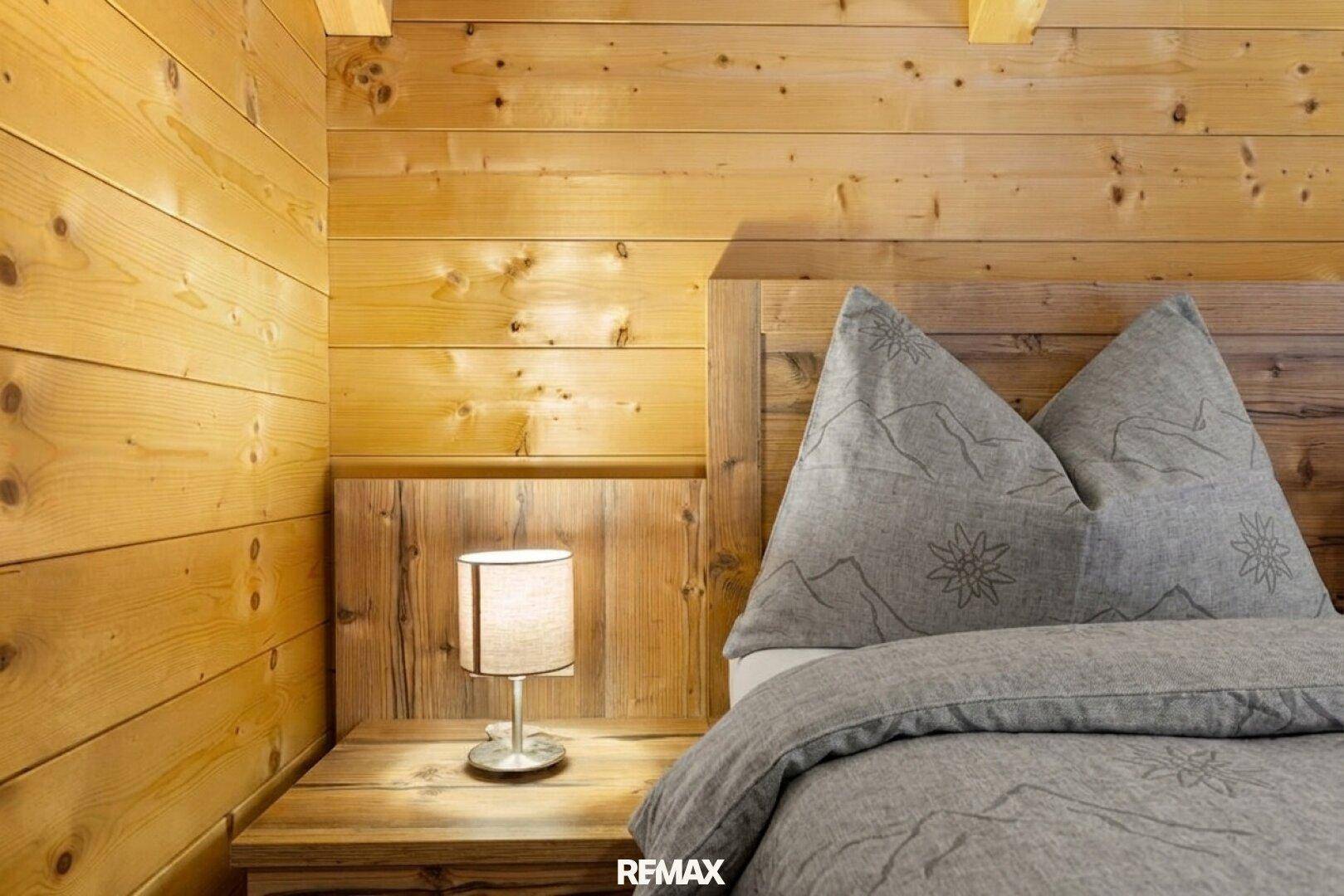 Nachttisch mit Lampe und alpiner Bettwäsche in einem gemütlichen Schlafzimmer.