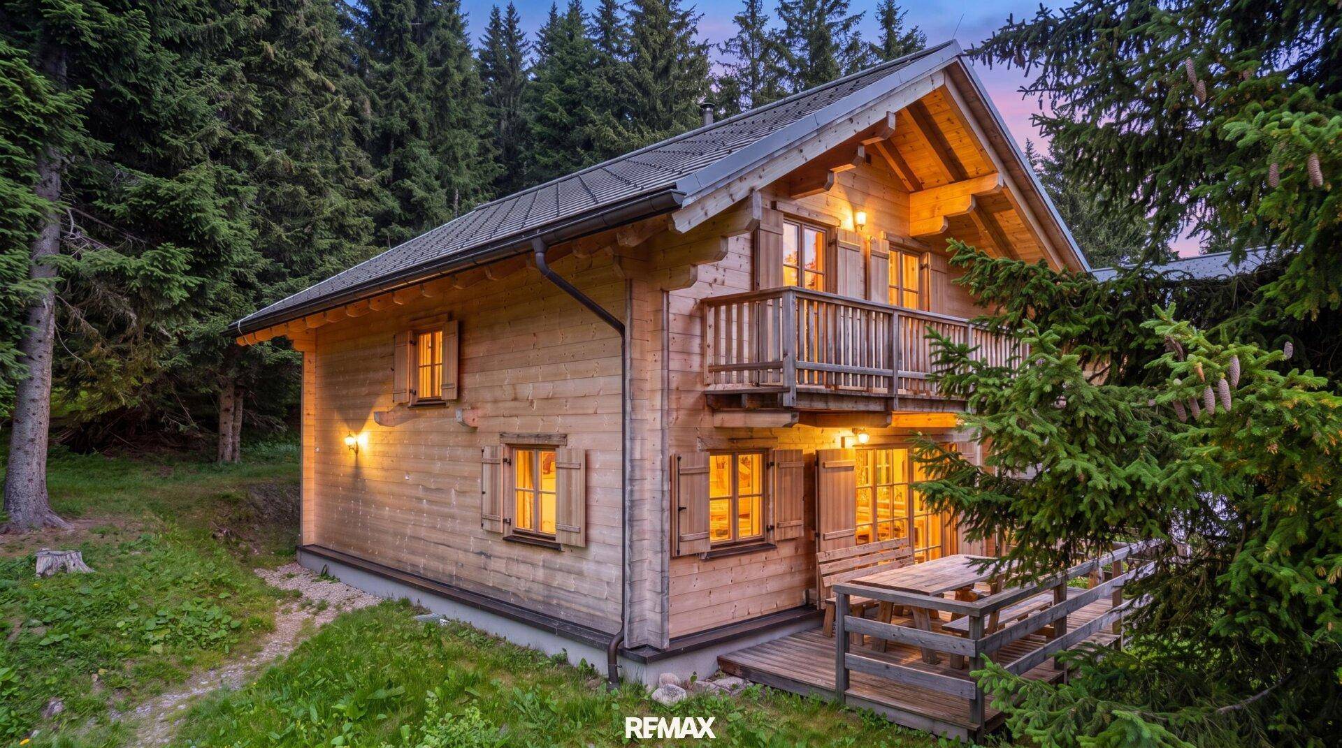 Charmantes Holzchalet umgeben von Bäumen mit Balkon und Terrasse im Wald.