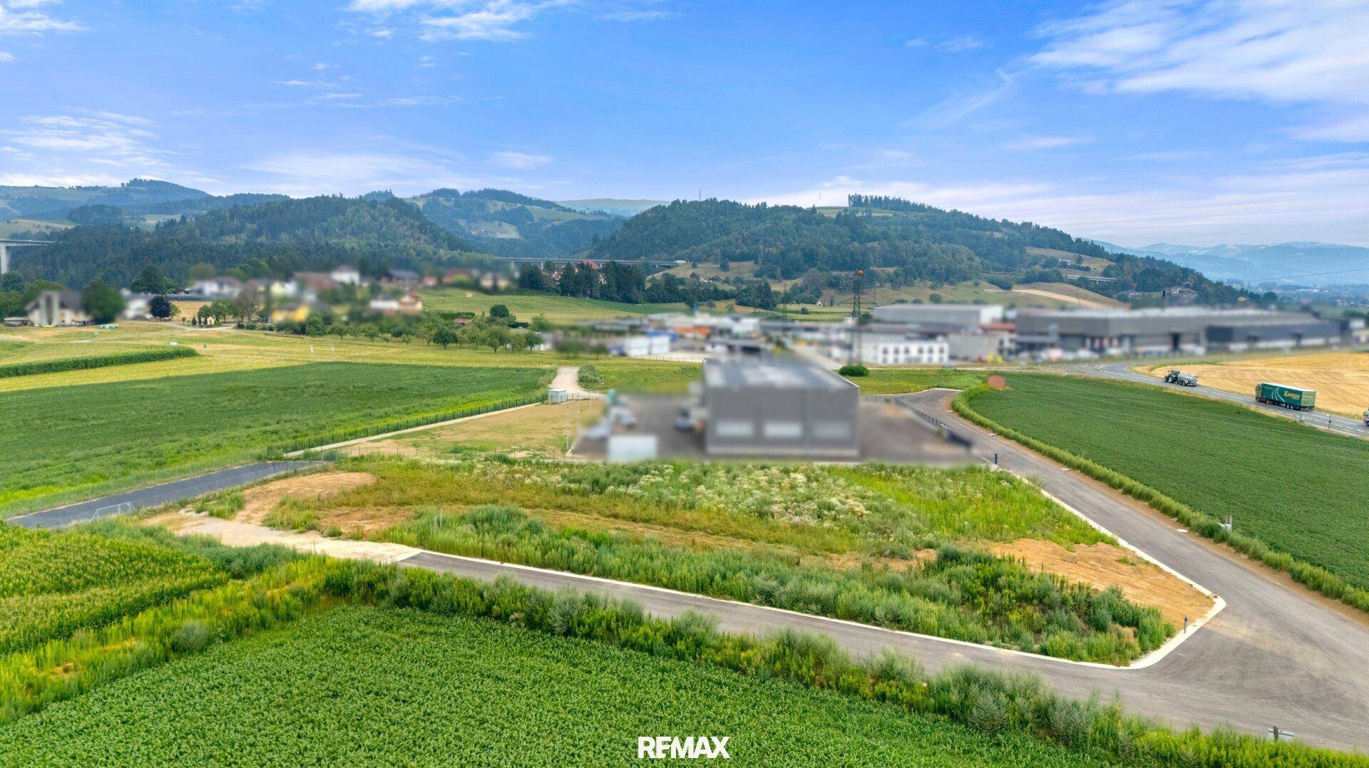 Ausblick auf eine ländliche Umgebung mit Feldern und einer Straße, die in der Ferne zu einer Siedlung führt.