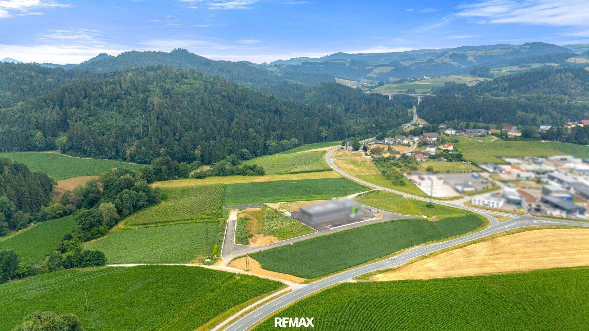 Weitläufige Luftaufnahme einer ländlichen Gegend mit Straßen, Feldern und bewaldeten Hügeln.