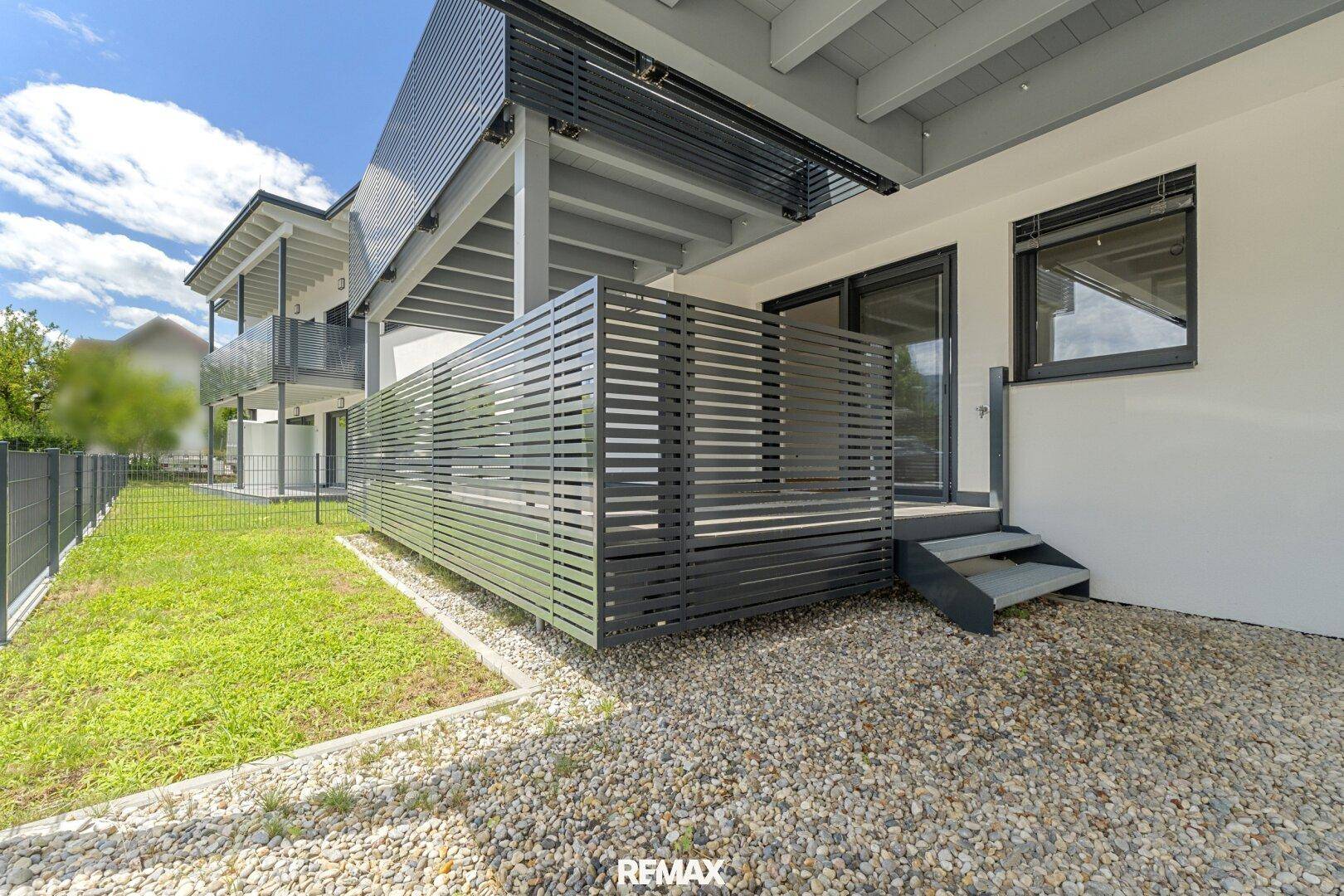 Private Terrasse im Erdgeschoss mit Kiesfläche, Sichtschutz und Zugang zum Garten.