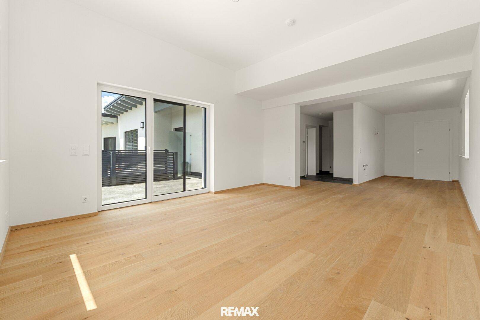 Offener Wohnbereich mit Eichenparkett und Zugang zu einem privaten Außenbereich.