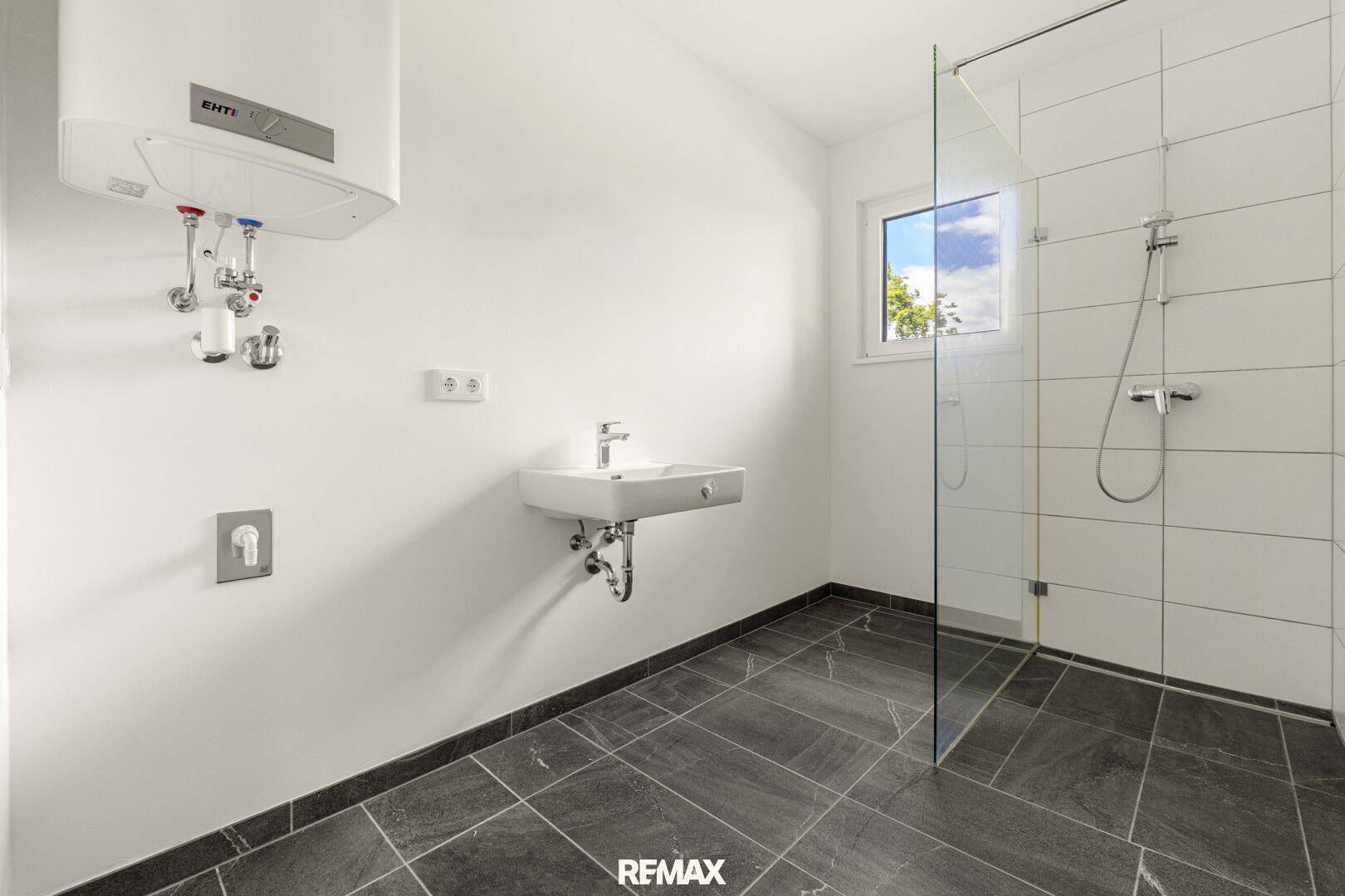 Modernes Badezimmer mit ebenerdiger Dusche, Fliesenboden und Fenster.