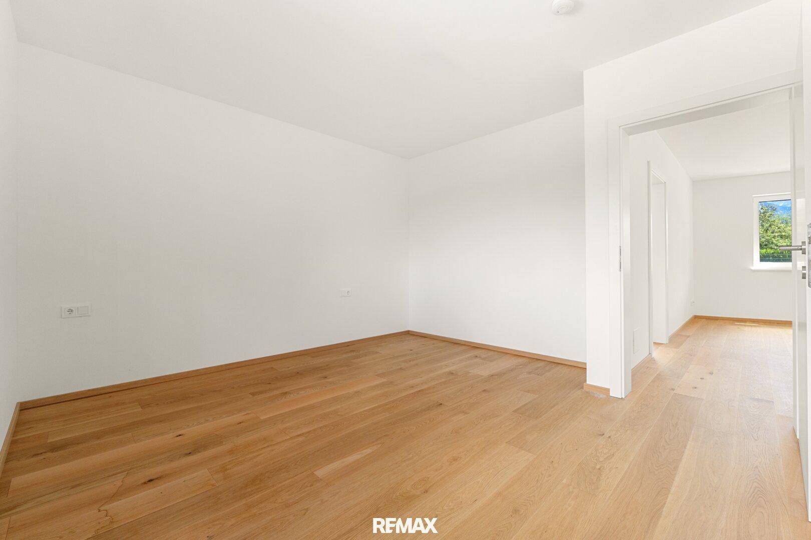 Helles Zimmer mit Eichenparkett und weiß gestrichenen Wänden, ideal als Schlafzimmer.