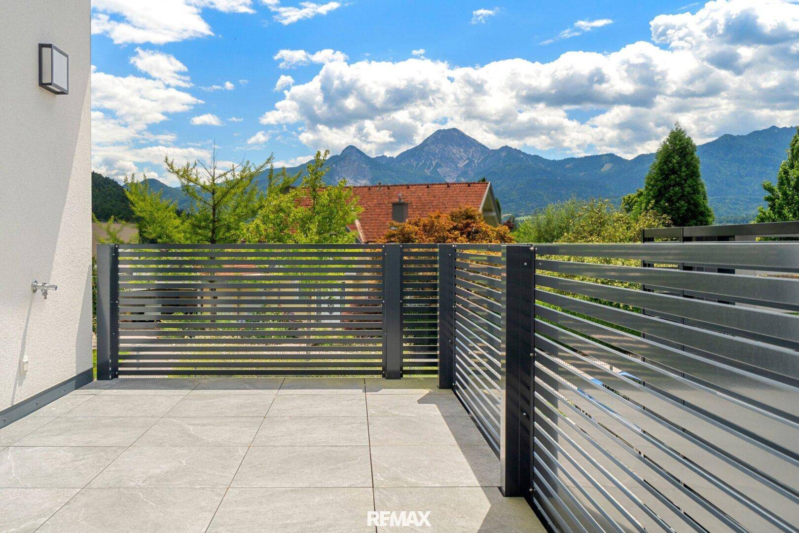 Heller Balkon mit Fliesenboden, modernem Geländer und beeindruckendem Bergblick.
