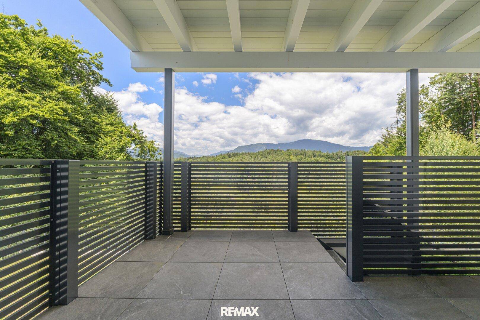 Geräumiger Balkon mit Fliesenboden, modernem Sichtschutz und Panoramablick auf die Berge.