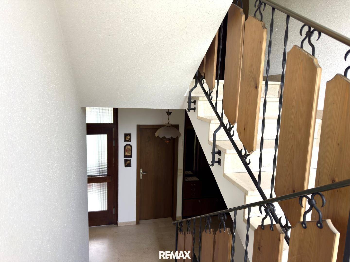 Detailansicht des Treppenhauses mit schmiedeeisernem Geländer und Holzverkleidung in einem hellen Flur.
