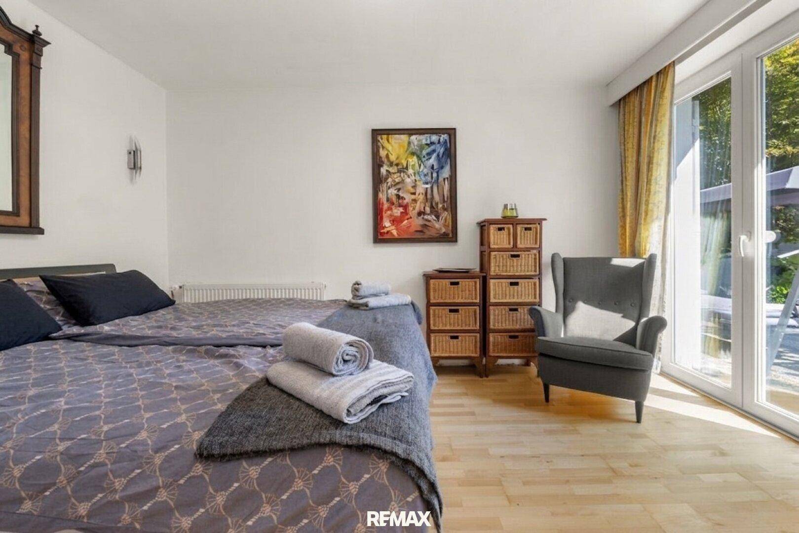 Helles Schlafzimmer mit Doppelbett, Holzboden und Zugang zur Außenterrasse.