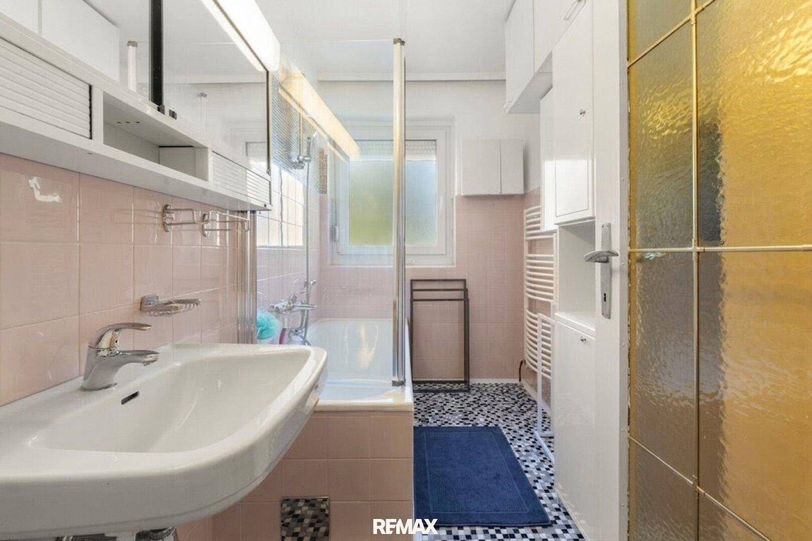 Badezimmer mit Badewanne, Waschbecken und rosa Fliesen im charmanten 80er-Jahre-Stil.