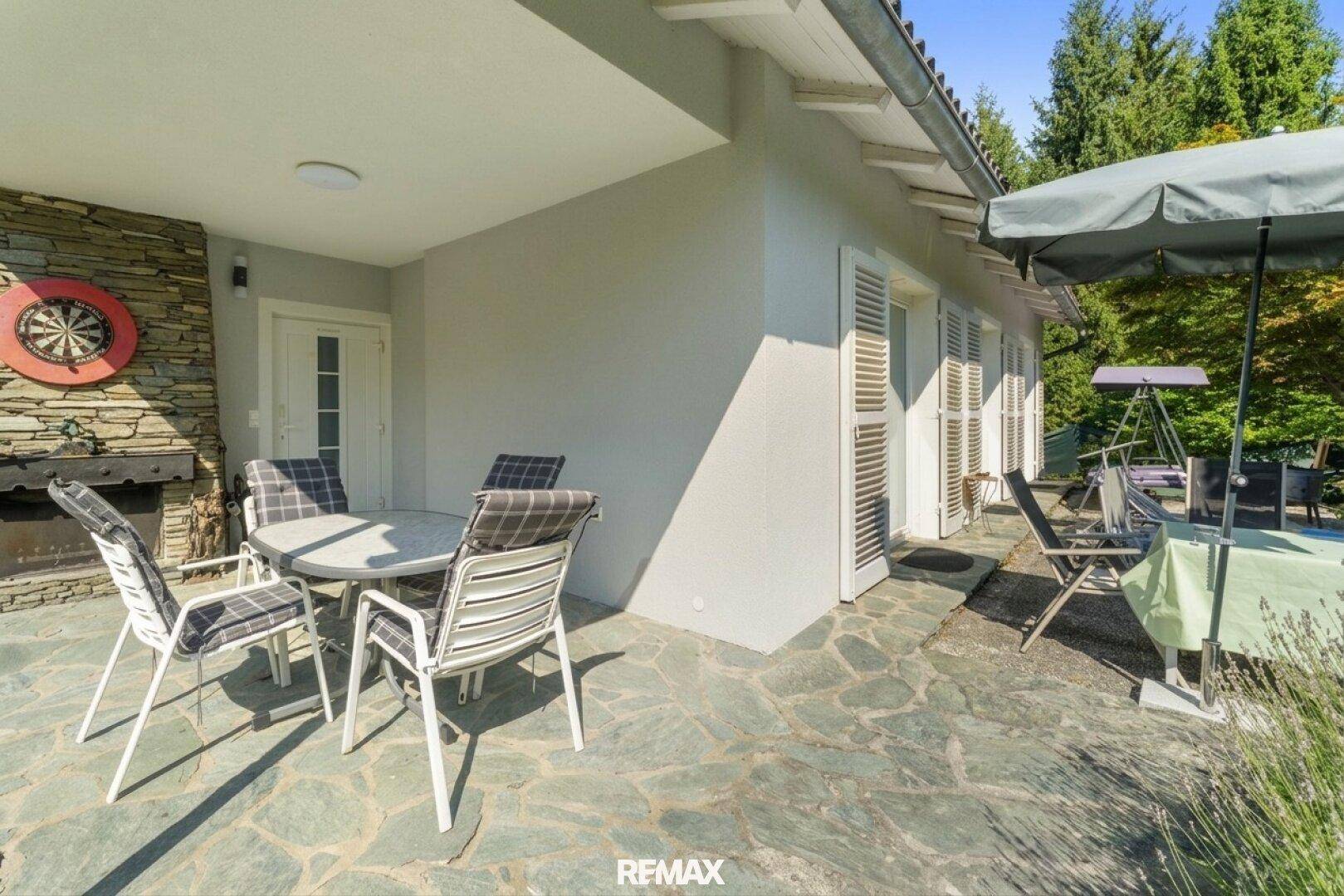 Geräumige Terrasse mit Außenkamin, Sitzgelegenheiten und Sonnenschirm für entspannte Stunden.
