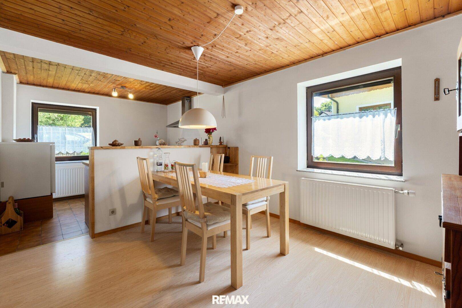 Heller Essbereich mit Holztisch und Stühlen, angrenzend an die Küche mit Holzdecke.