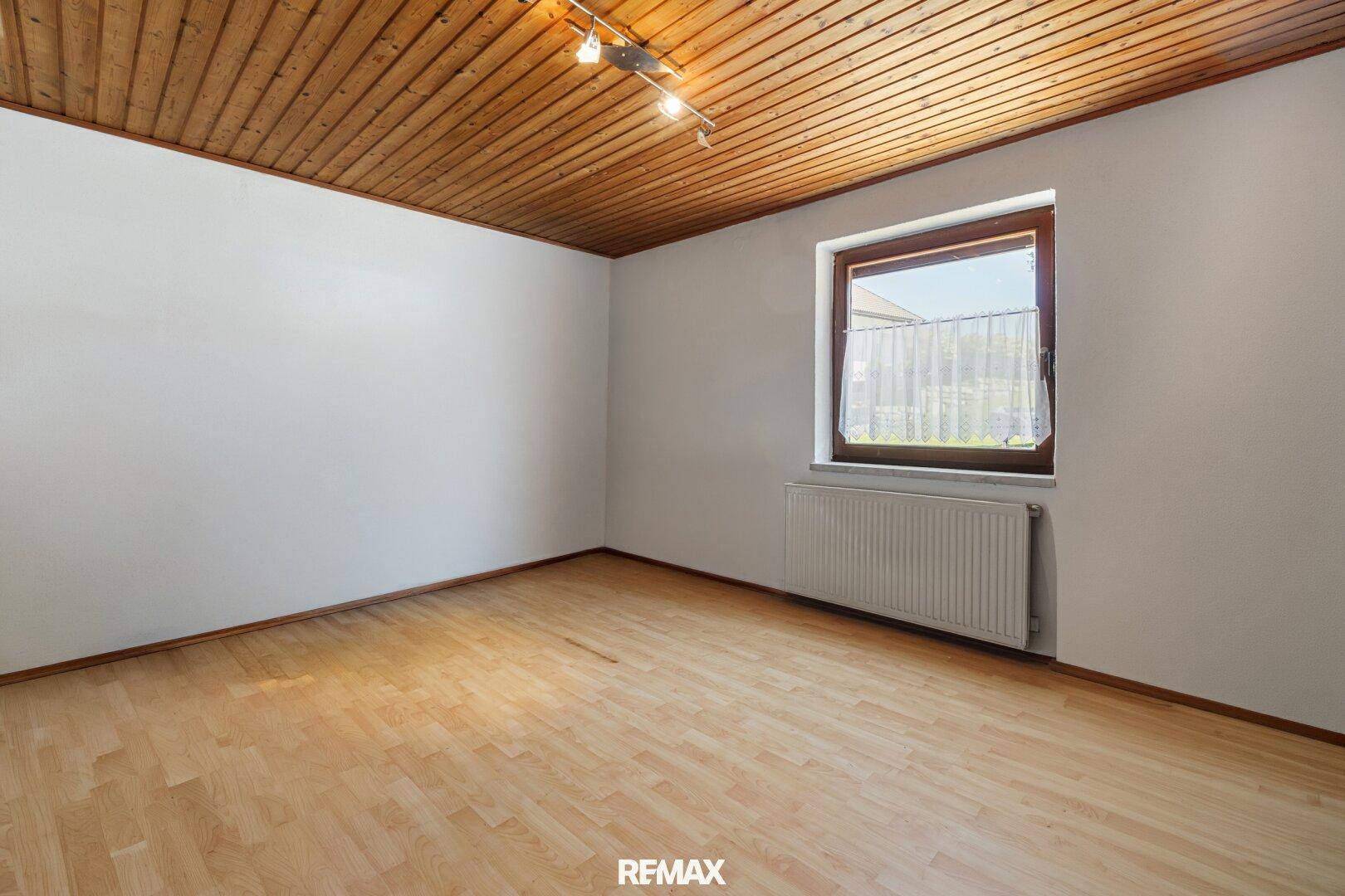 Leeres Zimmer mit Holzdecke und Parkettboden, ideal als Schlaf- oder Kinderzimmer.