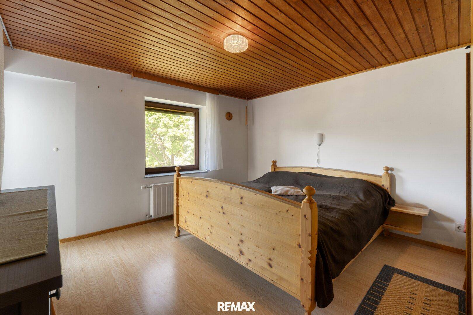 Schlafzimmer mit Holzbett, Parkettboden und Holzdecke, bietet eine warme Atmosphäre.