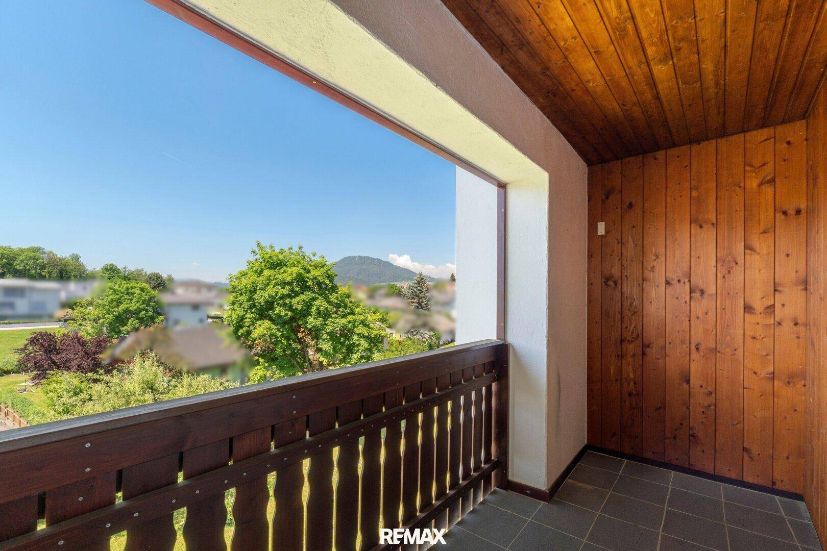 Überdachter Balkon mit Holzverkleidung und Fliesenboden, bietet einen weiten Blick.