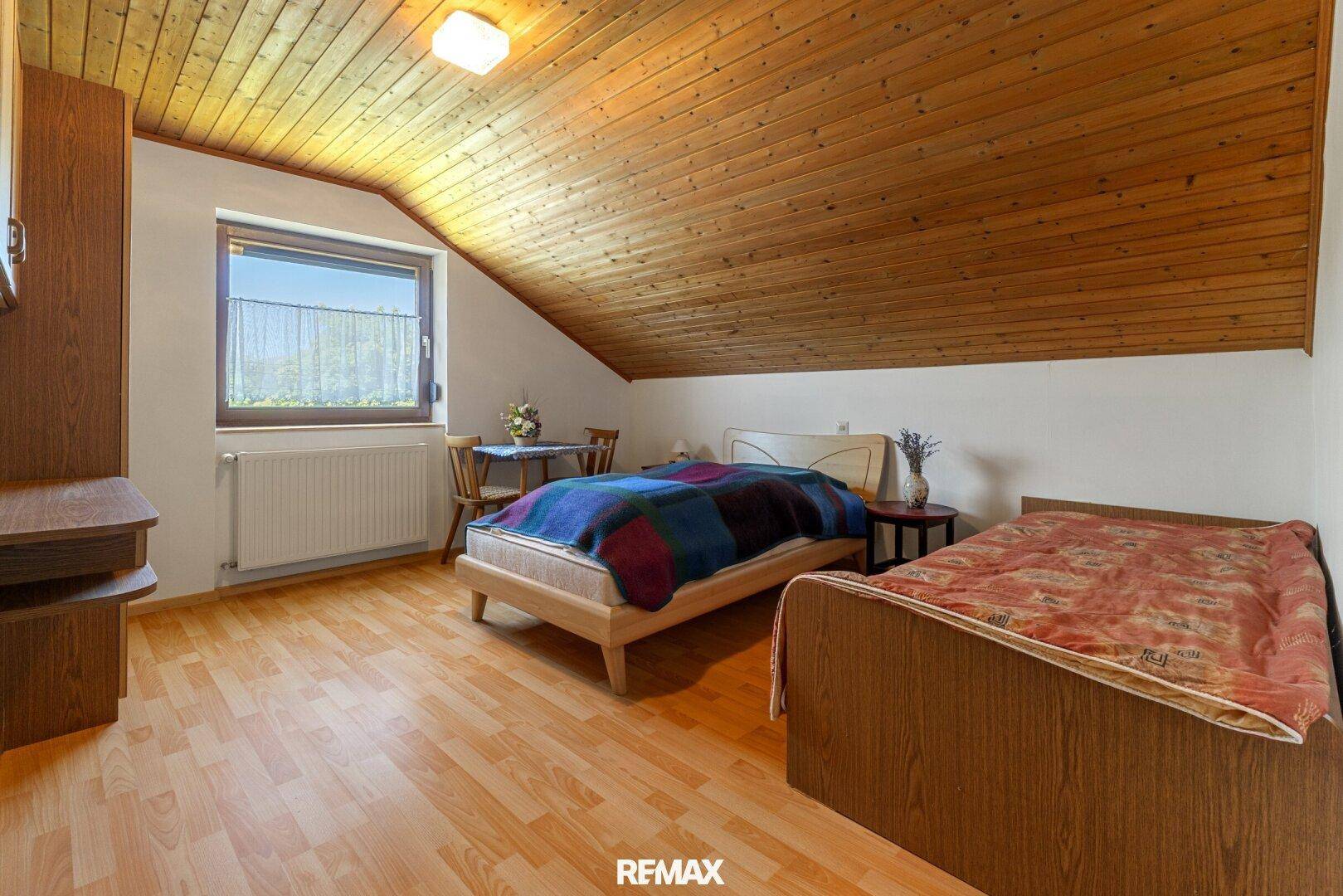 Schlafzimmer im Dachgeschoss mit Holzdecke, Laminatboden und zwei Einzelbetten.