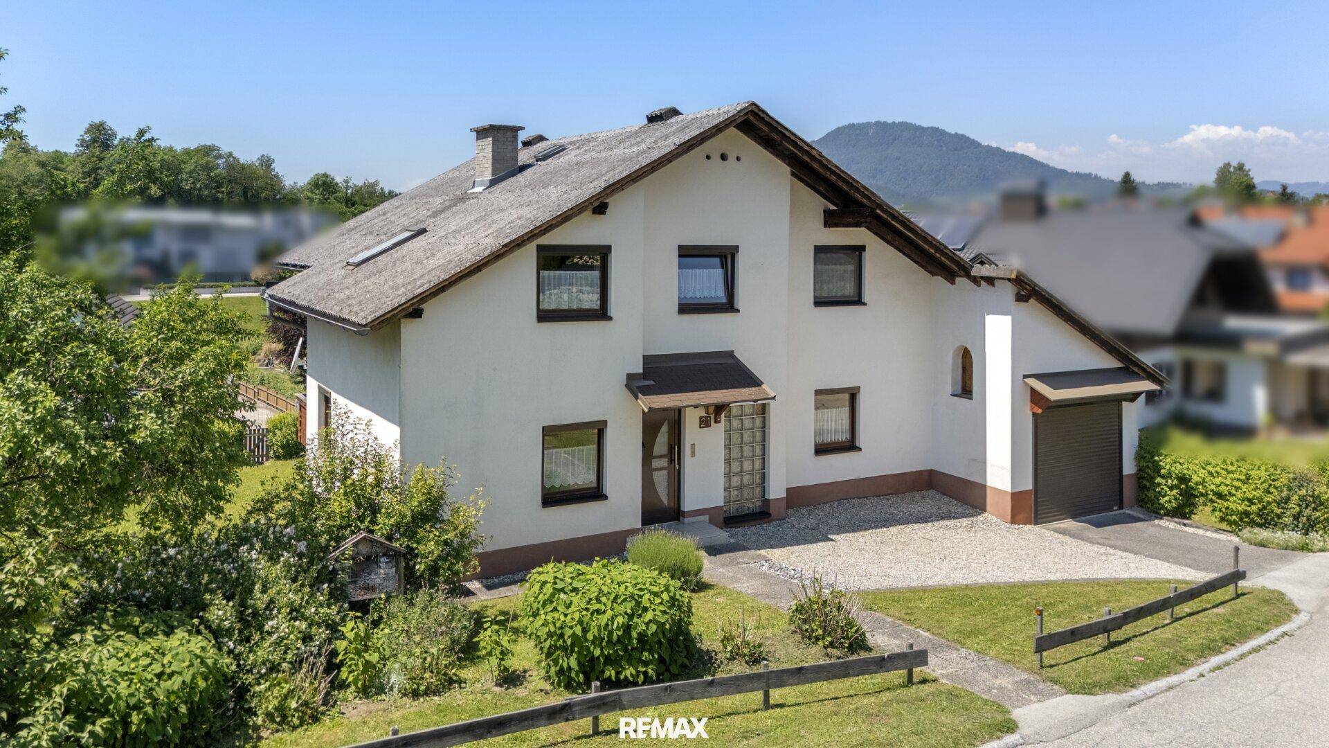 Freistehendes Einfamilienhaus mit Garage, weißer Fassade und gepflegtem Vorgarten.