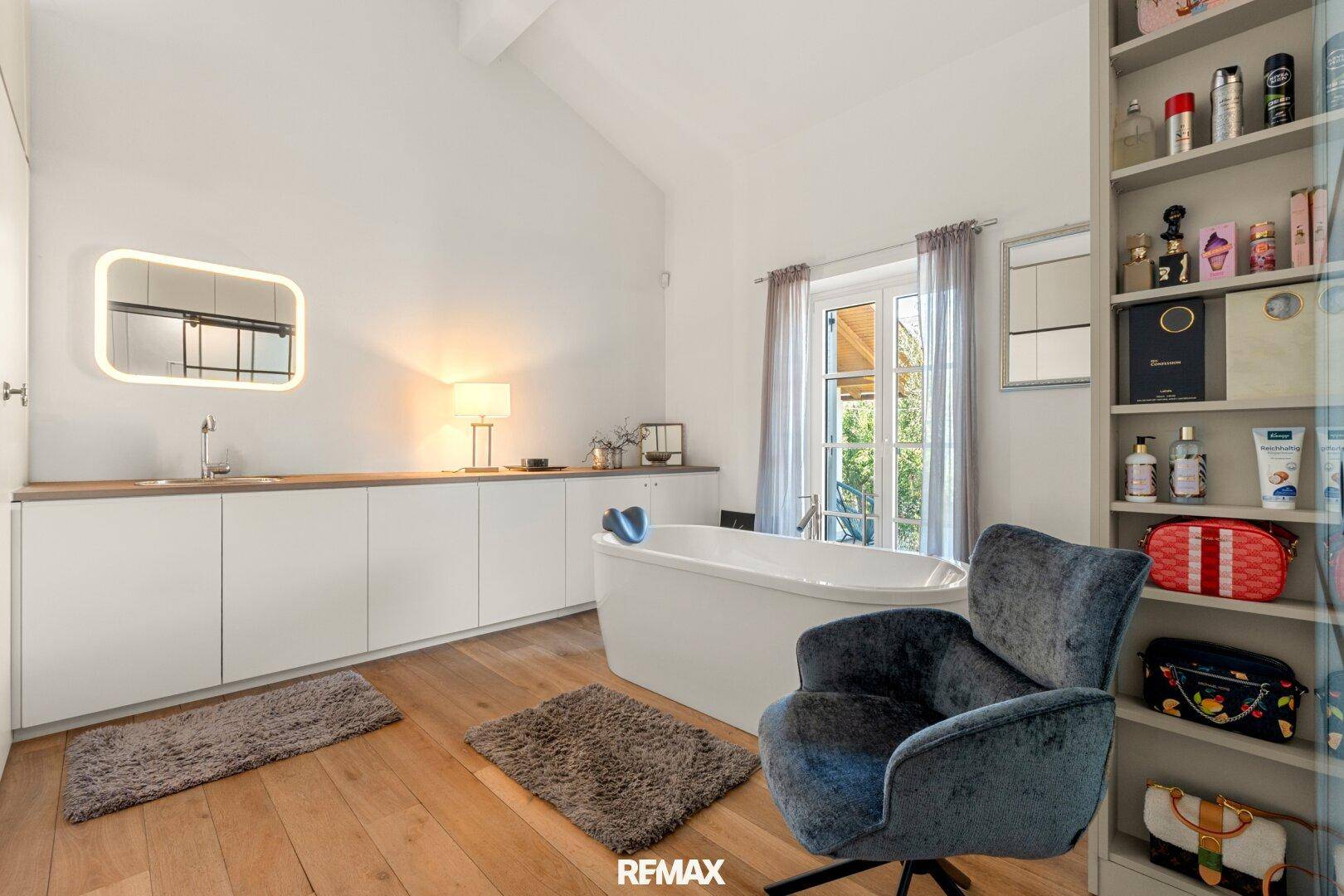 Helles Badezimmer mit Waschtisch, Spiegel und freistehender Badewanne.