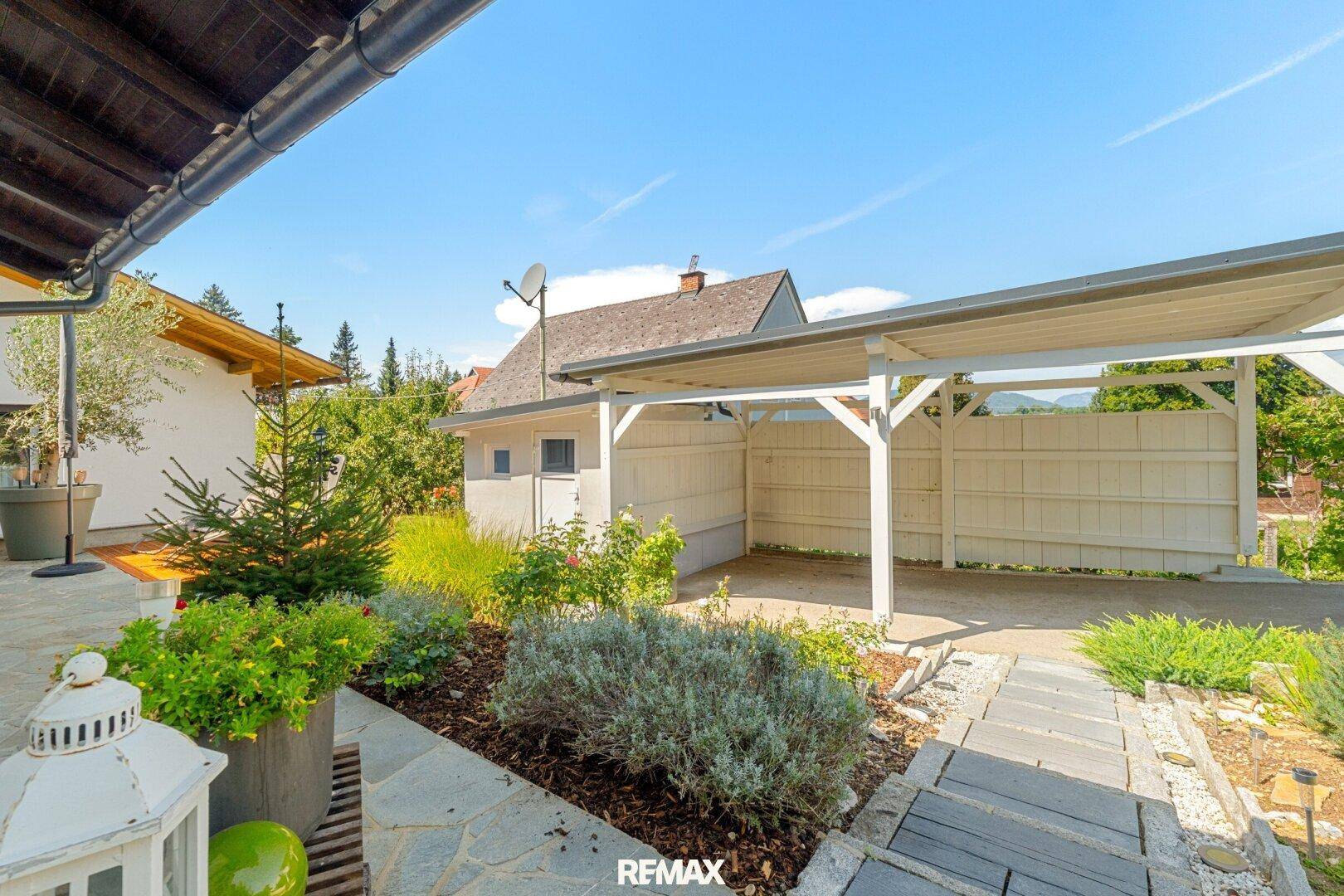 Gepflegter Vorgarten mit Bepflanzung, Carport und Blick auf die Umgebung.