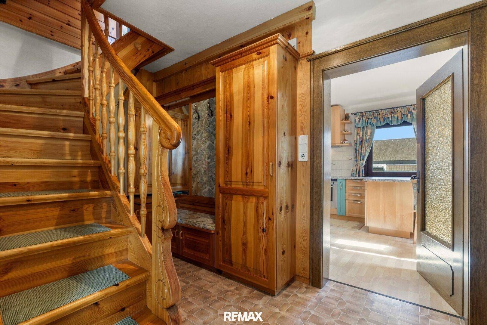 Gemütlicher Flur mit Holztreppe, Einbauschrank und Blick in die Küche.