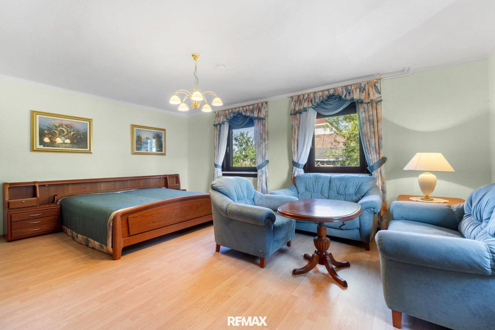 Helles Schlafzimmer mit Doppelbett, Sitzgelegenheiten und Laminatboden.
