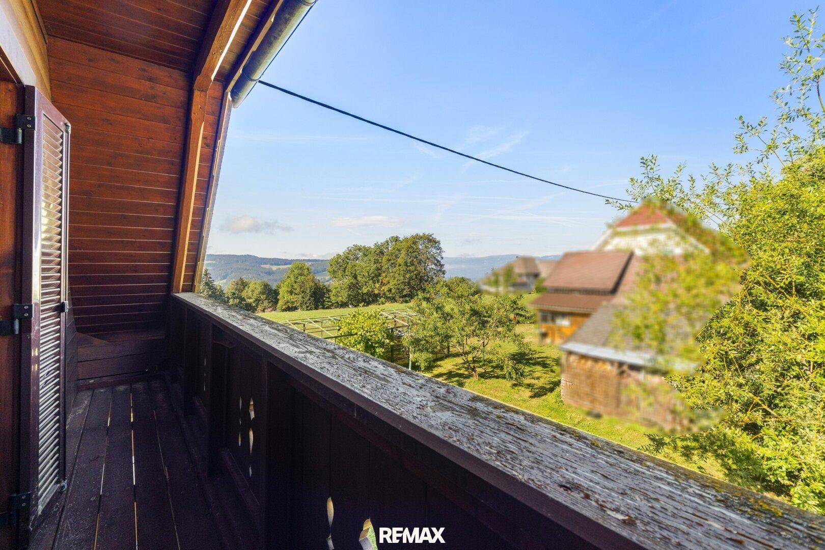 Holzbalkon mit weitem Blick über die grüne Landschaft und die Umgebung.