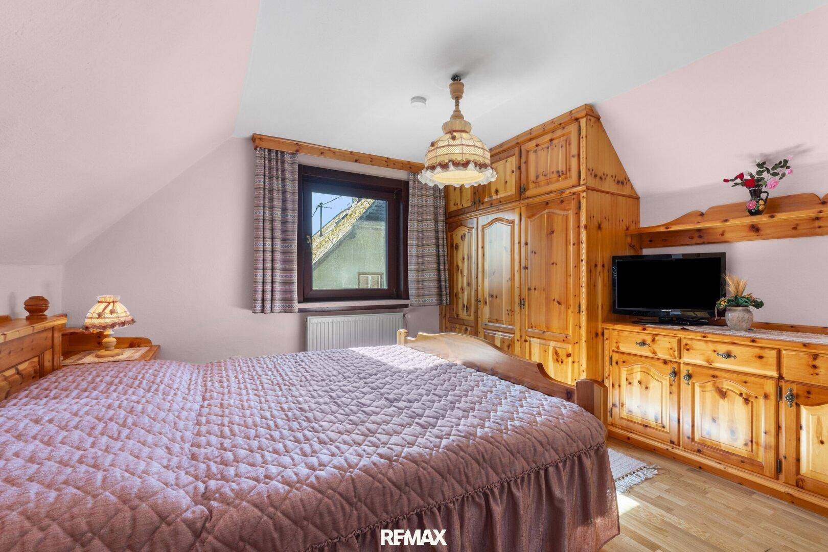 Schlafzimmer im Landhausstil mit Holzmöbeln, Doppelbett und Laminatboden.