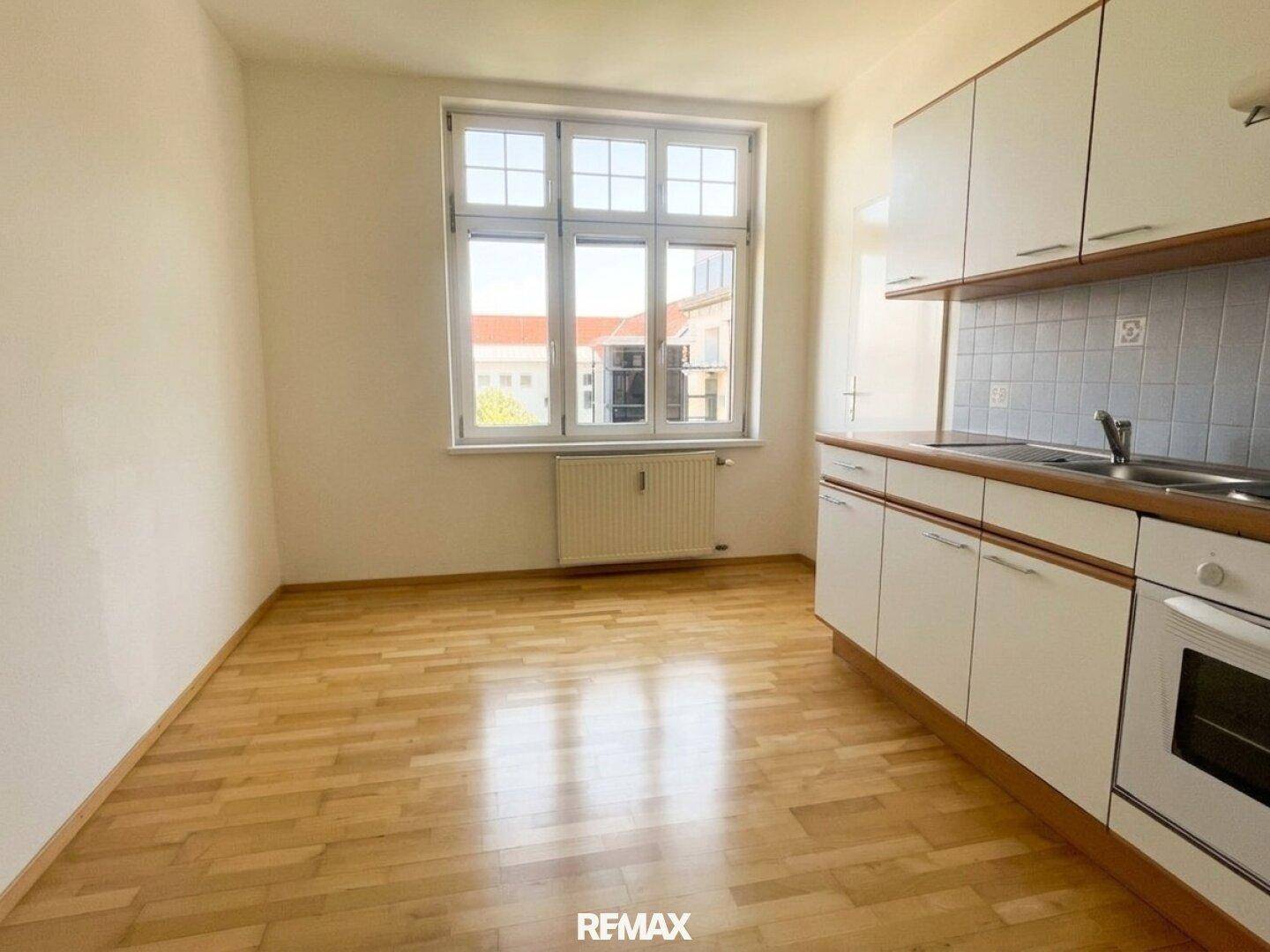 Küchenbereich mit Einbauküche und Fenster, das den Raum mit Tageslicht versorgt.